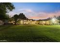 Vast backyard featuring lush green lawn, warm lighting, and a spacious patio area at 2106 E La Vieve Ln, Tempe, AZ 85284