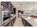 Modern kitchen with dark cabinets, stainless steel appliances, and a stylish tiled backsplash at 2792 N Acacia Way, Buckeye, AZ 85396