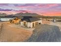 A stylish home exterior showcases a three-car garage and desert landscaping under a vibrant sunset sky at 35280 N Bell Rd, Queen Creek, AZ 85144