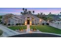 Charming home featuring a well-manicured lawn, mature trees, and inviting entrance at dusk at 1405 W Caribbean Ln, Phoenix, AZ 85023