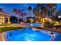Outdoor jacuzzi and pool area illuminated by night lights and palm trees at 1405 W Caribbean Ln, Phoenix, AZ 85023