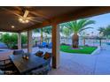 Covered patio with ceiling fan offers comfortable outdoor seating and views of the beautifully landscaped yard at 15954 W Sheila Ln, Goodyear, AZ 85395