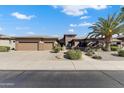 Inviting single-story home with lush landscaping, mature palm trees, and a spacious three-car garage at 20609 N Canyon Whisper Dr, Surprise, AZ 85387