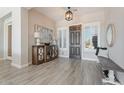 Elegant foyer featuring wood-look tile flooring, decorative table, and stylish lighting fixture at 30271 N 117Th Dr, Peoria, AZ 85383