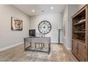 Bright home office featuring a desk, chair, decorative shelving, and an oversized clock at 30271 N 117Th Dr, Peoria, AZ 85383