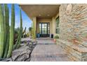 Inviting front entrance with stone accents, desert landscaping, and a modern glass door at 38199 N Tranquil Way, Carefree, AZ 85377