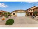 A tan home featuring a two car garage door and desert landscaping on a sunny day at 45068 W Alamendras St, Maricopa, AZ 85139