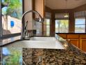 Close-up of a kitchen sink with granite countertops and a window with greenery outside at 4867 E Windstone Trl, Cave Creek, AZ 85331