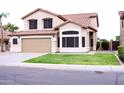 Inviting two-story residence showcasing a two-car garage, tiled roof, and lush green lawn at 488 W Harvard Ave, Gilbert, AZ 85233
