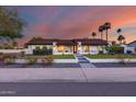 Charming home featuring manicured front yard, lush landscaping, and a welcoming entryway, all complemented by a colorful sunset backdrop at 5975 E Larkspur Dr, Scottsdale, AZ 85254