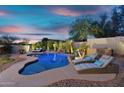 Beautiful backyard features a lagoon style pool with waterfalls and lounge chairs at dusk at 7354 E Norwood St, Mesa, AZ 85207