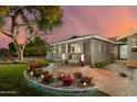 Attractive exterior with a seating area, manicured lawn, landscape lighting, and tasteful brick accents at 8229 E Devonshire Ave, Scottsdale, AZ 85251