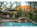 Backyard pool with rock waterfall feature and poolside dining area, set against a desert mountain backdrop at 10040 E Happy Valley Rd # 2022, Scottsdale, AZ 85255