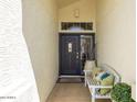 Charming front entrance featuring a decorative door and a cozy bench with pillows and potted plant at 15516 W Verde Ln, Goodyear, AZ 85395