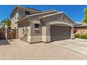 Exterior view of the property with a two-car garage, desert landscaping, and a secure fenced entry at 15604 N 173Rd Ln, Surprise, AZ 85388