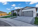 Stylish single-story home featuring a brick driveway, green artificial turf, and a grey garage door at 3842 E Alameda Ln, Gilbert, AZ 85298