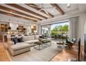 Open-concept living room featuring exposed beams, hardwood floors, and access to the outdoor patio at 8220 E Sharon Dr, Scottsdale, AZ 85260