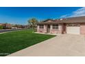 Well-maintained single-story home with a lush green lawn, brick exterior, and convenient attached garage at 9816 N 95Th Dr # A, Peoria, AZ 85345