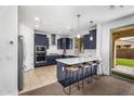 Modern kitchen with stainless appliances, breakfast bar, and tile floors, flowing into a carpeted living space at 10425 E Corbin Ave, Mesa, AZ 85212