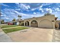 A single-story home showcases an arched carport and a well-manicured lawn under a bright, cloudy sky at 1059 E 9Th Ave, Mesa, AZ 85204