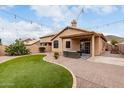 Inviting backyard featuring an artificial grass area, brick border, and cozy patio with string lights at 11163 E Laurel Ln, Scottsdale, AZ 85259