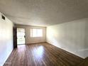 Bright living room featuring wood-look flooring, a front-facing window, and an entry door for easy access at 141 N Date -- # 7, Mesa, AZ 85201