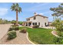 Expansive backyard with a lush lawn, desert landscaping, mature palm tree, and outdoor living spaces at 1515 E Saratoga Ct, Gilbert, AZ 85296