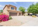 Two-story home with a three-car garage and a long driveway, with desert landscaping and green foliage at 16228 W Crocus Dr, Surprise, AZ 85379
