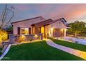 Charming single-story home with manicured lawn, paver walkway, and warm exterior lighting at sunset at 1322 W Spur Dr, Phoenix, AZ 85085