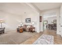 Open-concept living room with tan carpet, neutral walls, and stylish furnishings leading to the dining area at 1322 W Spur Dr, Phoenix, AZ 85085