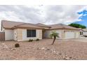 Single-story home featuring a three-car garage, xeriscaping, and a mature palm tree at 10513 W Wilshire Dr, Avondale, AZ 85392