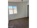 Bedroom with carpet, window, and white walls, awaits personalization, offers ample natural light, and renovation potential at 11918 W Aster Dr, El Mirage, AZ 85335
