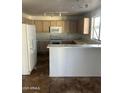 An open kitchen with white appliances, light wood cabinets, and tiled floors at 11918 W Aster Dr, El Mirage, AZ 85335