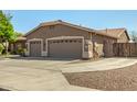Attractive home featuring a three car garage and desert landscaping in the front yard at 13609 W Vermont Ave, Litchfield Park, AZ 85340