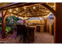 Backyard outdoor kitchen with bar seating, built-in grill, mini fridge, and stylish pergola cover at 1502 W Wagner Dr, Gilbert, AZ 85233