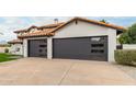 A house with a large driveway, with dark gray garages featuring contemporary window accents at 10775 N 101St St, Scottsdale, AZ 85260