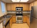 Galley kitchen with stainless steel appliances, light wood cabinets and granite countertops at 5757 W Eugie Ave # 1038, Glendale, AZ 85304