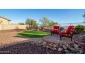 Inviting backyard showcases a cozy seating area with two red chairs, enhancing the outdoor living experience at 18033 W Tecoma Rd, Goodyear, AZ 85338