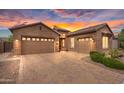 Beautiful brick home with a paver driveway and a well-manicured front yard at sunset at 22296 E Maya Rd, Queen Creek, AZ 85142