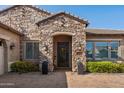 Inviting stone entryway with a wrought iron door, decorative plants, and stylish lighting fixtures at 22302 E Russet Rd, Queen Creek, AZ 85142