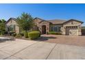 Charming single-story home with three-car garage, manicured landscaping, stone accents, and brick driveway at 22302 E Russet Rd, Queen Creek, AZ 85142