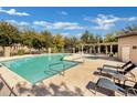 Community pool featuring a pergola, lounge chairs, and mature trees in a fenced area at 2491 N 149Th Ln, Goodyear, AZ 85395