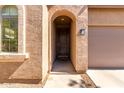 Close-up of front entrance featuring a textured facade, arched doorway, and decorative window at 37852 W Merced St, Maricopa, AZ 85138