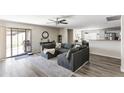 Open-concept living room with sliding glass doors, ceiling fan, and comfortable gray sectional sofa at 42430 W Oakland Dr, Maricopa, AZ 85138