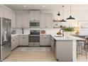 Well-lit kitchen features stainless steel appliances, light gray cabinets, white subway tiles, and center island at 7646 W Park St, Laveen, AZ 85339