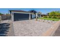 Spacious gray brick driveway leads to a modern home with a gray garage door and desert landscape at 3010 E Glenrosa Ave, Phoenix, AZ 85016