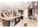 Modern kitchen with stainless steel appliances, granite countertops, dark wood cabinetry, and an open layout at 18543 W Denton Ave, Litchfield Park, AZ 85340