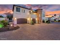Elegant home exterior with a stone tower, two-car garage, and a spacious paver driveway at dusk at 3675 N 59Th Pl, Phoenix, AZ 85018