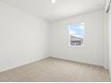 Bright bedroom with neutral carpet, white walls, and a window providing natural light at 37215 W Patterson St, Maricopa, AZ 85138