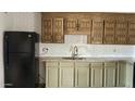 Close-up of a kitchen featuring tile countertops, vintage wood cabinets, and black appliances at 7961 W Campbell Ave, Phoenix, AZ 85033